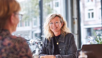 Lachende vrouw bij gesprek in café