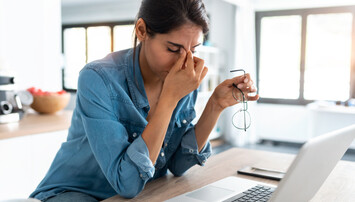 Persoon met hoofdpijn voor een laptop
