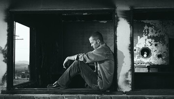 Zwart-wit foto van een man in een raamkozijn