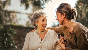 Vrouw slaat arm om oudere dame heen